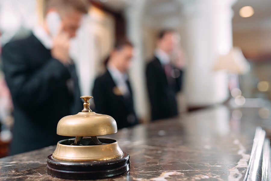 Hospitality-Insurance-Front-Desk-Associate-on-the-Phone-with-a-Bell-on-the-Desk-of-a-Luxury-Hotel